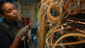 Young female network engineer of African American ethnicity fixing and connecting cables in server room - Powered by Shutterstock - Get 15% off with code: PIKWIZARD15