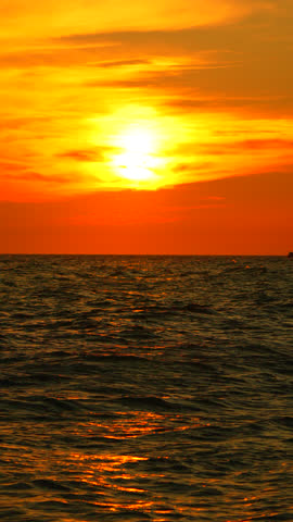 Sunset Ocean Seascape: Vibrant orange sky, setting sun over calm sea, idyllic evening scene.