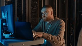 Focus on male Caucasian programmer working on wireless laptop in server room with female African American colleague - Powered by Shutterstock - Get 15% off with code: PIKWIZARD15