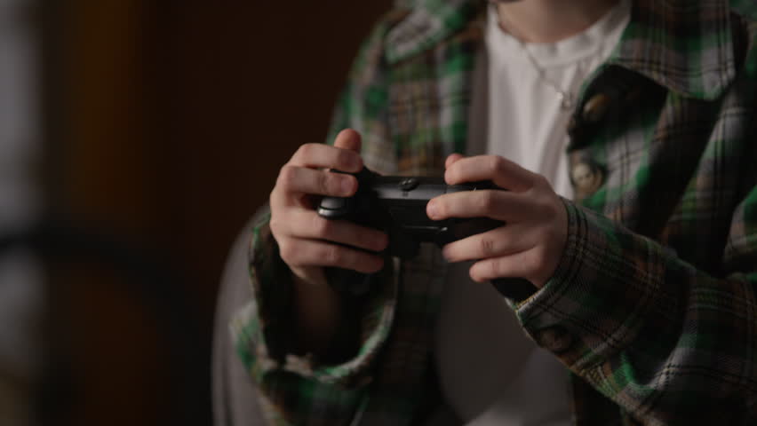 Concentrated angry mad furious Caucasian little girl teen child kid gamer schoolgirl in wireless headphones earphones using controller throwing frustration lost in the video game losing defeat at home