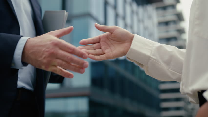 Close up business handshake two unrecognizable multiracial diversity people in city handshaking hands gestures talking African American businesswoman woman female Caucasian man businessman male deal
