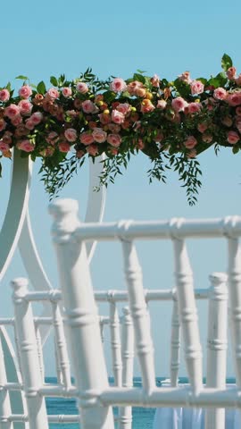 wedding decor, white wedding arch decorated with roses, wedding ceremony on the beach, preparation for wedding ceremony on the beach.