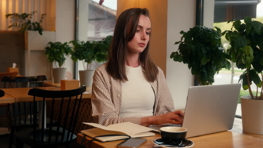 European woman concentrated busy in cafeteria manager analyzing data girl female studying in cafe remote write preparing to exams writing notes with laptop net working businesswoman business distant - Powered by Shutterstock - Get 15% off with code: PIKWIZARD15