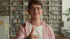Teenage guy in books store library in high school college looking at camera smiling positive showing thumb up like gesture recommend learning Caucasian man male student teen boy teenager education - Powered by Shutterstock - Get 15% off with code: PIKWIZARD15