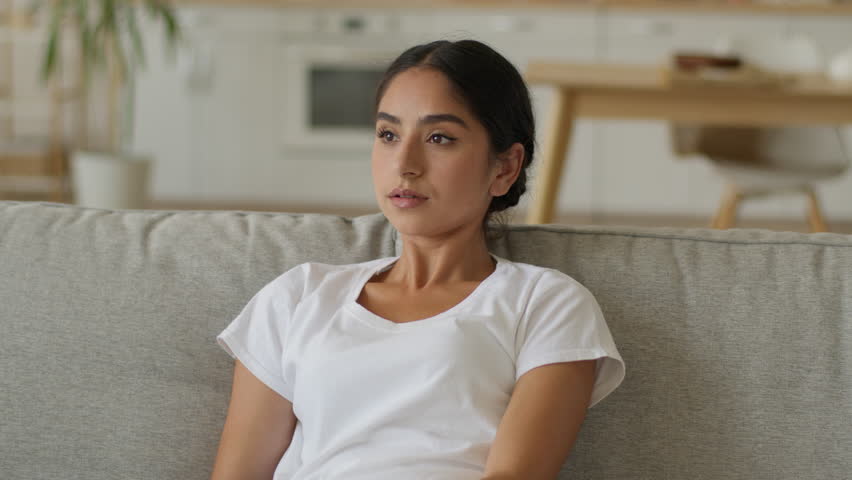 Broken air conditioner high temperature ventilation problem at home suffering frustrated sweated Indian woman Arabian girl female relaxing on couch summer hormonal trouble health medicine failure