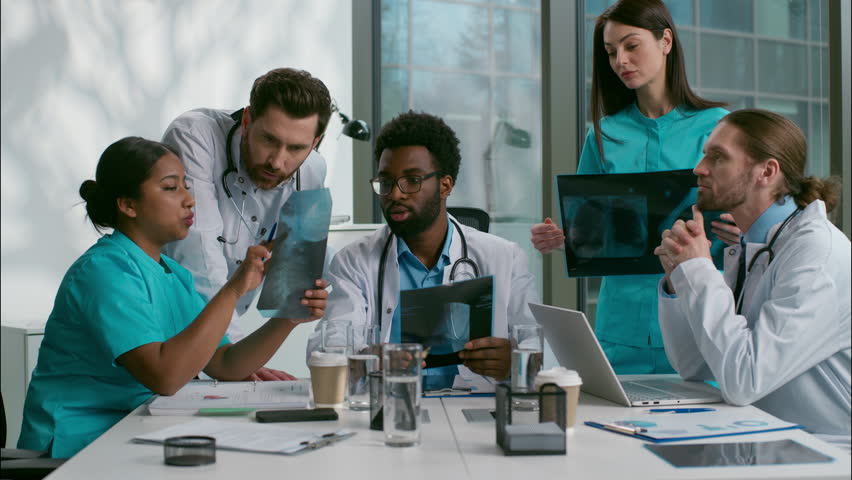 Multiethnic doctors medical diagnostic team meeting heath research xray analyzing African men Indian Caucasian women diverse nurse surgeon medicare five people talk discuss checkup results at clinic