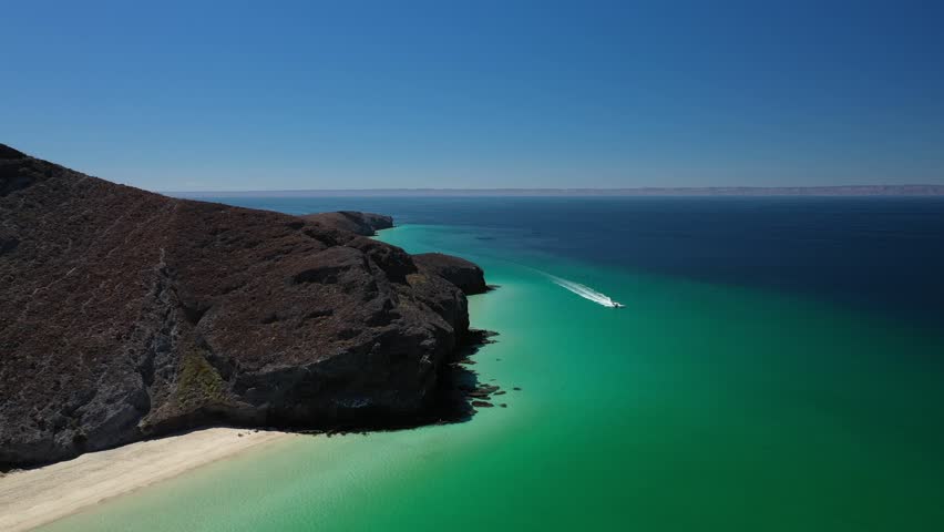 Aerial view of a motorboat creating a wake in the clear turquoise waters of Balandra beach in Baja California Sur, Mexico