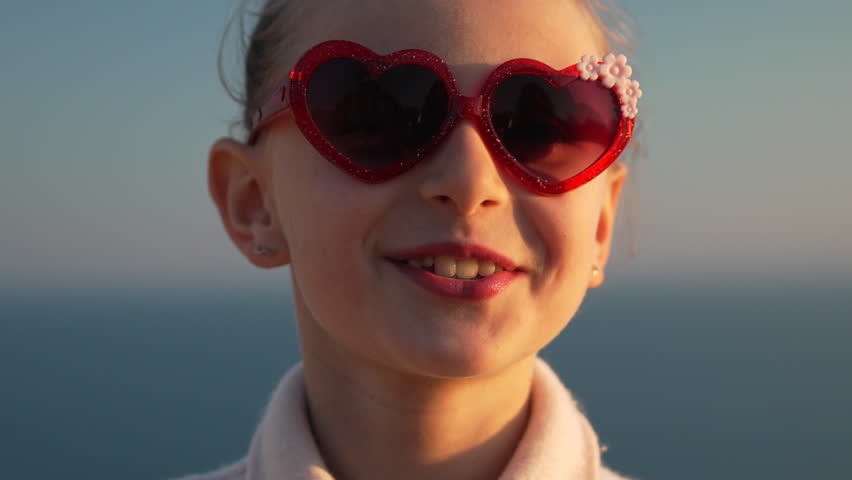 Girl Sunglasses Smiling young girl wearing heart shaped sunglasses smiling outdoors at sunset
