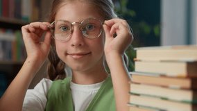 Smart successful excellent student Caucasian little girl child kid schoolgirl school pupil learner putting on eyeglasses eyewear glasses looking at camera preparing to exam learning books read indoor - Powered by Shutterstock - Get 15% off with code: PIKWIZARD15