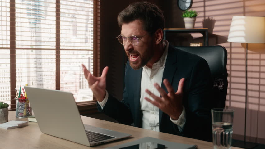 Mad furious stressed angry business work online video call yelling talking rage fury problem conference conflict arguing shout laptop nervous middle-aged Caucasian man businessman male guy in office