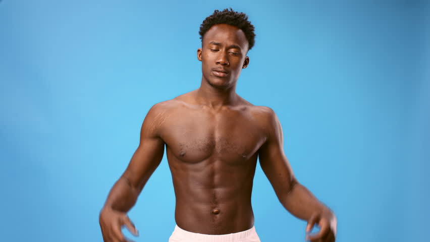 Young African American man flexing muscles against a blue background