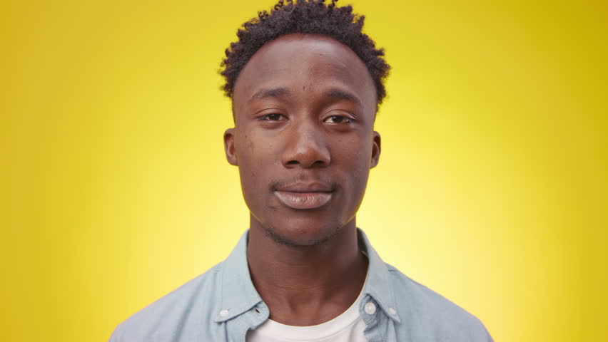 Young African American man posing against a vibrant yellow background in 4K