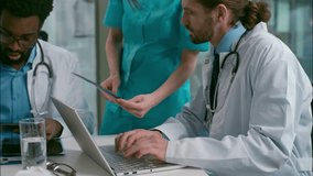 Doctors meeting multiethnic five people medical professionals healthcare discussion African Indian Caucasian surgeon team diverse medic colleagues use computer laptop analyzing xray health at clinic - Powered by Shutterstock - Get 15% off with code: PIKWIZARD15