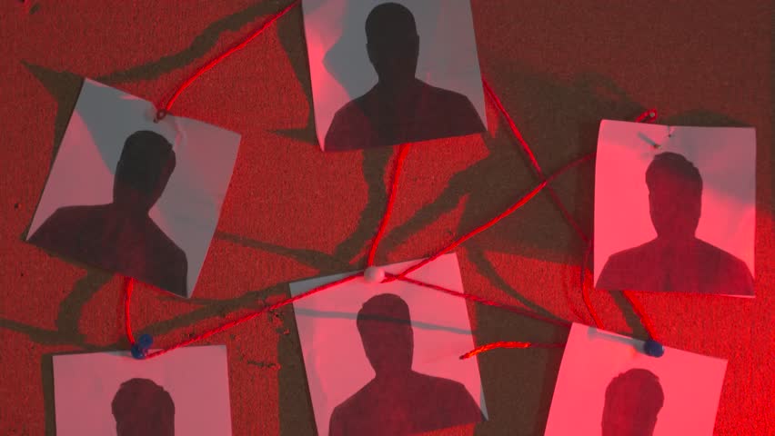 Criminal investigation board with suspect photos connected by red thread on cork background