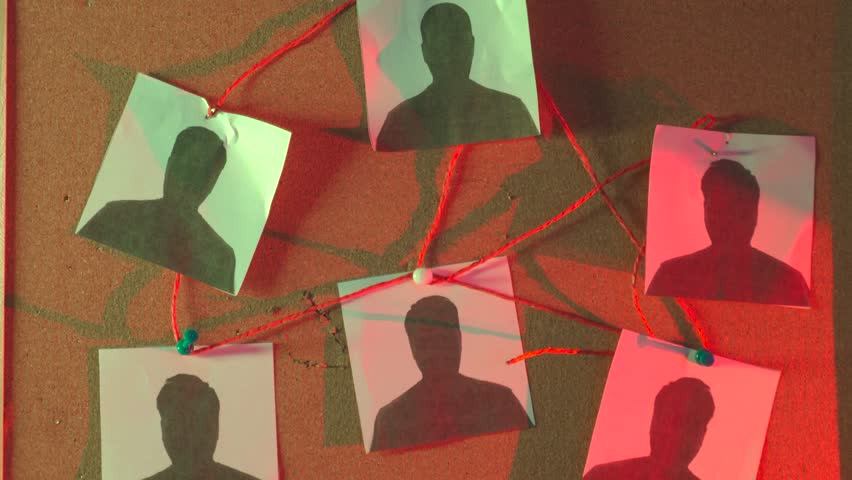 Criminal investigation board with suspect photos connected by red thread on cork background