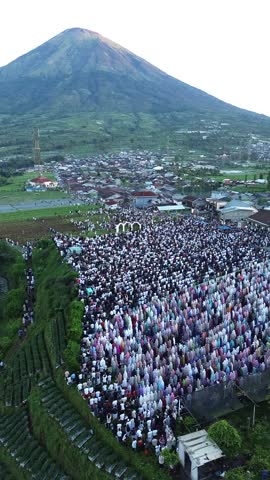 view of an Eid al-Fitr or Eid al-Adha prayer event held en masse in the open air. Thousands of people gathered and lined up neatly in the fields or rice fields that had been prepared for the worship.