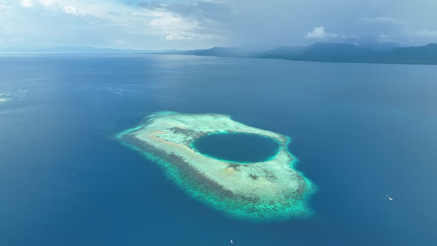 Seen from an aerial view, a picturesque atoll is found in the Molucca Sea near the island of Halmahera, Indonesia. Atolls form as the volcanic islands they surround slowly sink over geologic time.