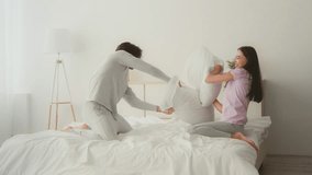 Couple enjoying playful pillow fight in bright bedroom during daytime - Powered by Shutterstock - Get 15% off with code: PIKWIZARD15