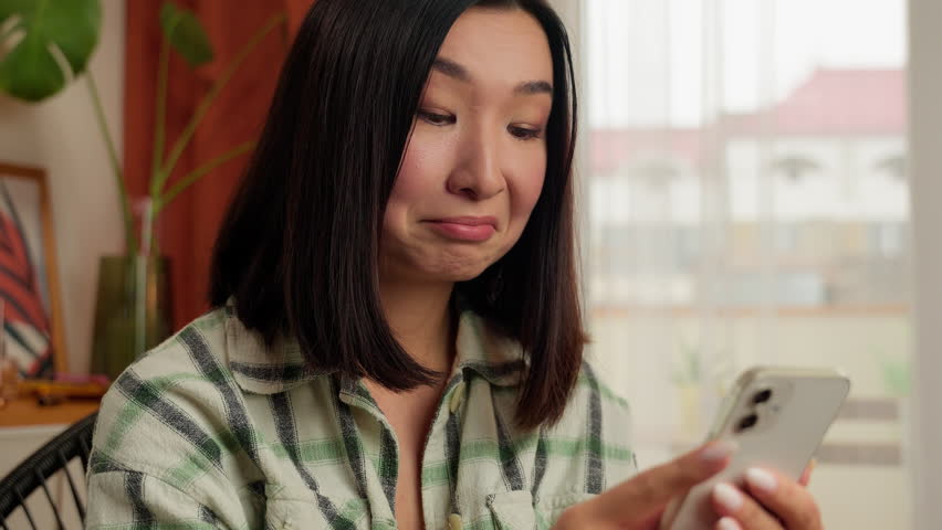 Shocked Asian Korean woman amazed female online message home indoors wonder astonish app mobile phone smartphone reading good news surprised wow excited happy lady smiling social media scrolling girl