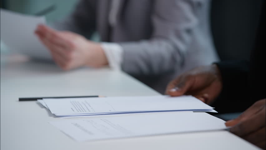 Close up unrecognizable African American man reading paper sheets document male guy businessman business manager meeting financial deal offer contract agreement in office partnership working paperwork