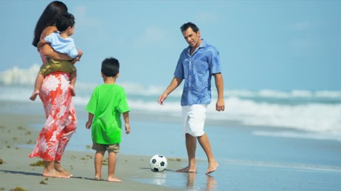 Hispanic young loving family spending vacation on beach playing football shot on RED EPIC