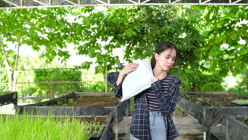 Asian teenage student working in vegetable garden carrying white sack outdoor sustainable agriculture experience responsibility organic farming education learning motion teamwork effort slowmotion