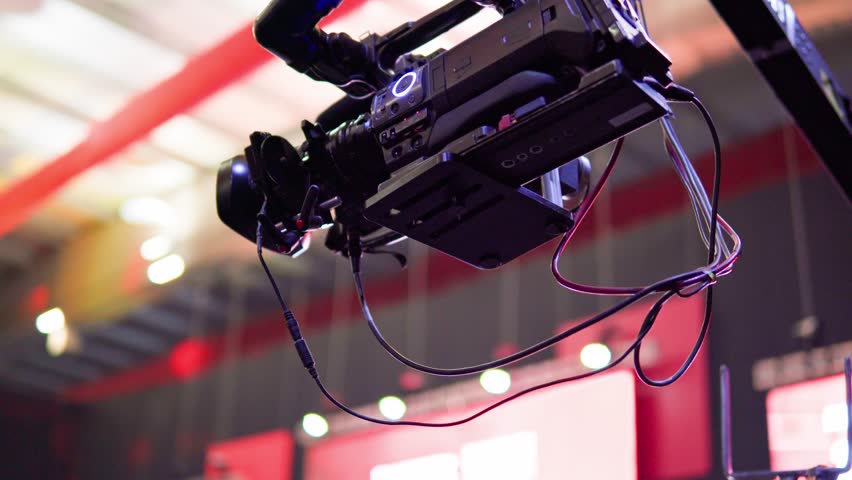 Professional broadcasting camera hanging on a crane, capturing footage in a large venue