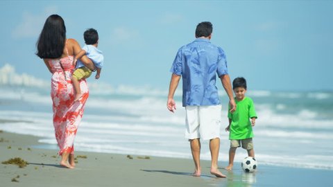 Latin American young loving family spending holiday on beach playing football shot on RED EPIC