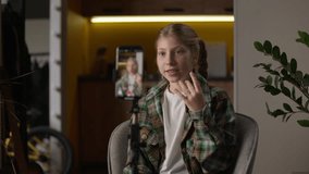 Happy smiling famous little girl Caucasian teen child kid influencer schoolgirl at home record video blog waving hand greeting hello vlog talking mobile phone camera on tripod recording social media - Powered by Shutterstock - Get 15% off with code: PIKWIZARD15