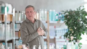 Senior man suffering from heart attack or cardiac issue, holding chest while standing in pharmacy, seeking medication - Powered by Shutterstock - Get 15% off with code: PIKWIZARD15
