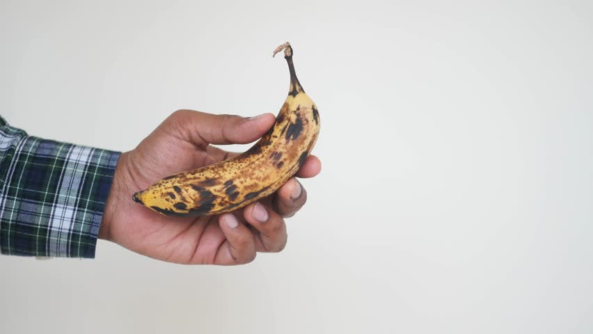 Holding a ripe banana in one hand with a casual grip