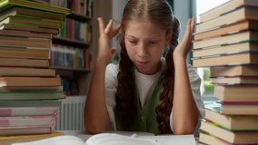 Angry irritated annoyed Caucasian little girl schoolkid child school kid schoolgirl learner pupil student sit desk two piles books writing pen textbook schoolwork irritation anger overworked indoors - Powered by Shutterstock - Get 15% off with code: PIKWIZARD15