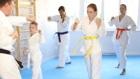 Teen girl and her family repeat movements and learn fighting techniques during martial arts lesson. Experienced man unrecognizable instructor conducts personal karate training for large family - Powered by Shutterstock - Get 15% off with code: PIKWIZARD15