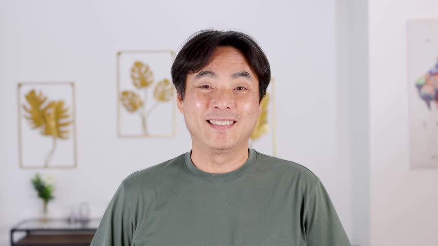 A man smiles and gives a thumbs up in a well-lit room with decorative wall art
