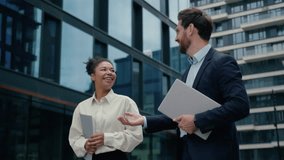 Two multiracial business people colleagues walking in city smiling friendly happy talking African American businesswoman woman female with Caucasian man businessman male work discuss holding folders - Powered by Shutterstock - Get 15% off with code: PIKWIZARD15