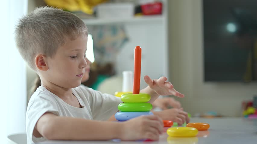 Brother sister play with constructor toy at house. Siblings assemble rings on pyramid. play with constructor at home. Brother sister bond through play. Educational play with constructor toy at house.