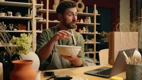 Happy joyful creative Caucasian talented craftsman man male guy businessman artisan small business owner holding pottery bowl decoration stoneware talking online video call laptop computer sell indoor - Powered by Shutterstock - Get 15% off with code: PIKWIZARD15