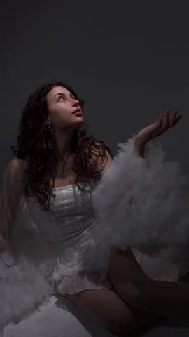 Beautiful young girl in a white dress and cape in a photo studio. Photoshoot. Posing. Photo model.