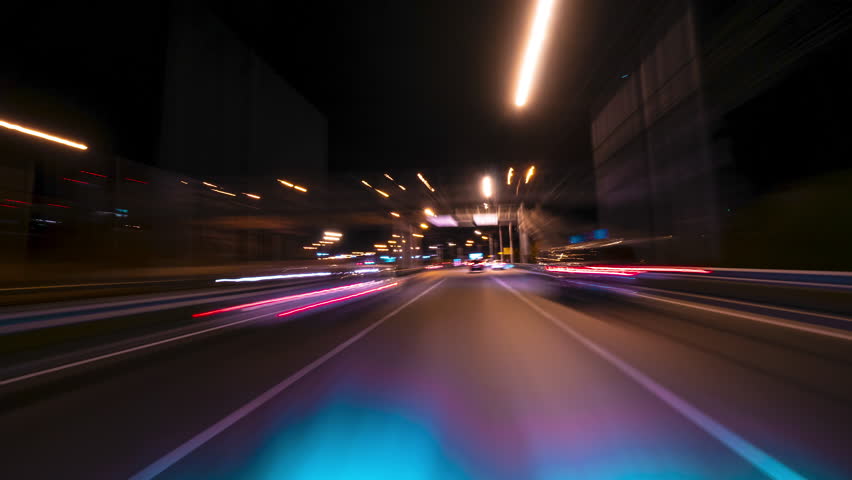 A Car Speeds Down the City Highway. Chaotic Lights Blur Into Bright Streaks. The Simulation of High-speed Movement Captures the Rhythm of the City. Trip Travel Concept. 4K Point of View Hyperlapse
