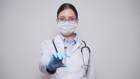 Smiling female doctor in white lab coat and gloves poised with medical syringe, representing vaccination or medical treatment, against light white background - Powered by Shutterstock - Get 15% off with code: PIKWIZARD15