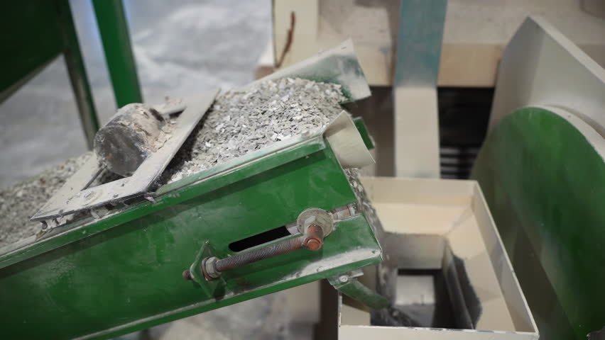 Recycled waste material transported by conveyor in manufacturing workshop. Eco friendly production process with usage of reusable supplies