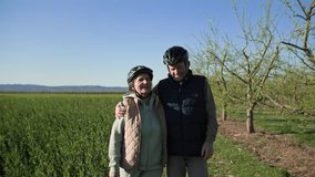 elderly couple walking arm in arm through green fields along fruit trees in countryside - Powered by Shutterstock - Get 15% off with code: PIKWIZARD15