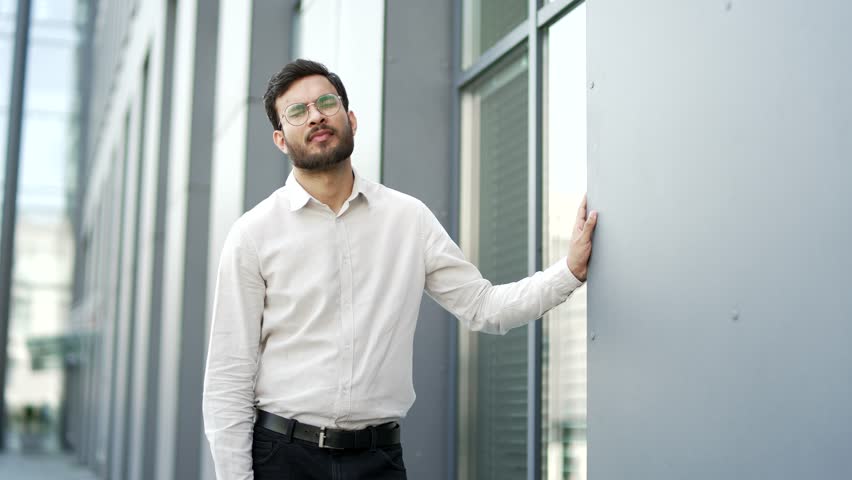 Businessman feels stomach pain while standing on street near business office building. Sick man has heartburn, gastritis, bloating or poisoning. An unhealthy male suffers from spasms and constipation