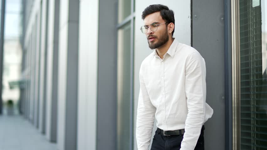 Unhealthy businessman suffering from nausea, wants to vomit while standing on the street near an office building. An unwell male feels bad, has a stomach ache, poisoning or problems with digestion