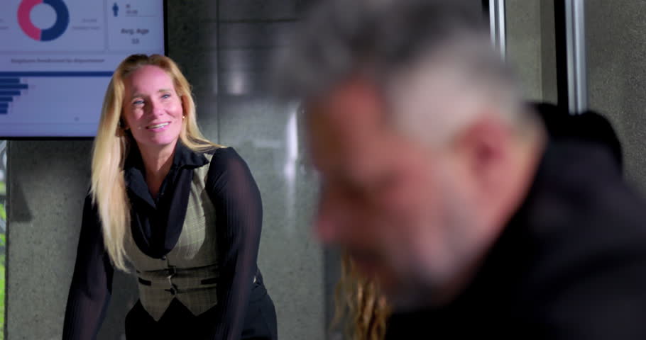Smiling businesswoman laughing spontaneously during office meeting, casual and relaxed atmosphere with charts in background, professional woman enjoying workplace moment