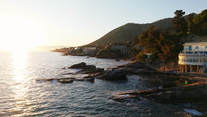 Sunset drone footage of Genoa coastline with clear skies and calm waters