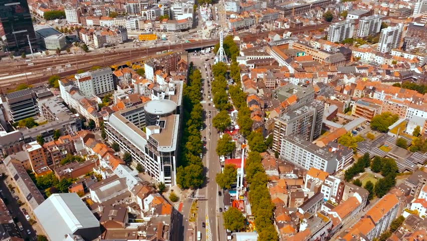 Aerial drone footage flying over Brussels Belgium central city where red rooftops with medieval buildings and Midi railroad station traintracks visible during sunny day in Europe historic city.