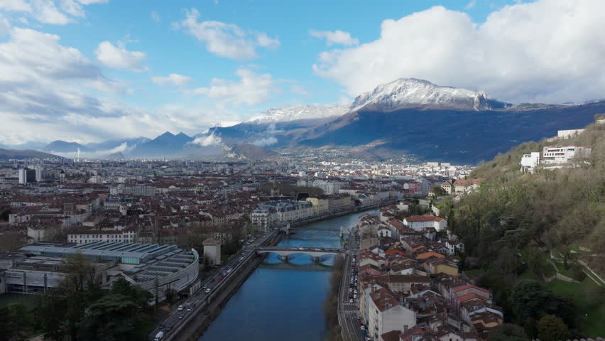 Aerial view of Grenoble city center, showcasing the river Isere and its bridges and snow capped mountains in the French Alps