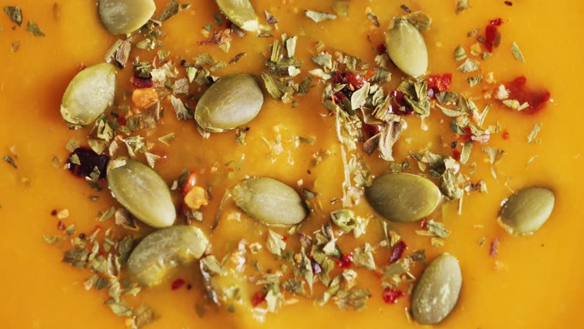 Autumn vegetable cream soup close-up seasoned with aromatic spices and seed pumpkin. Concept of texture. High quality 4k footage