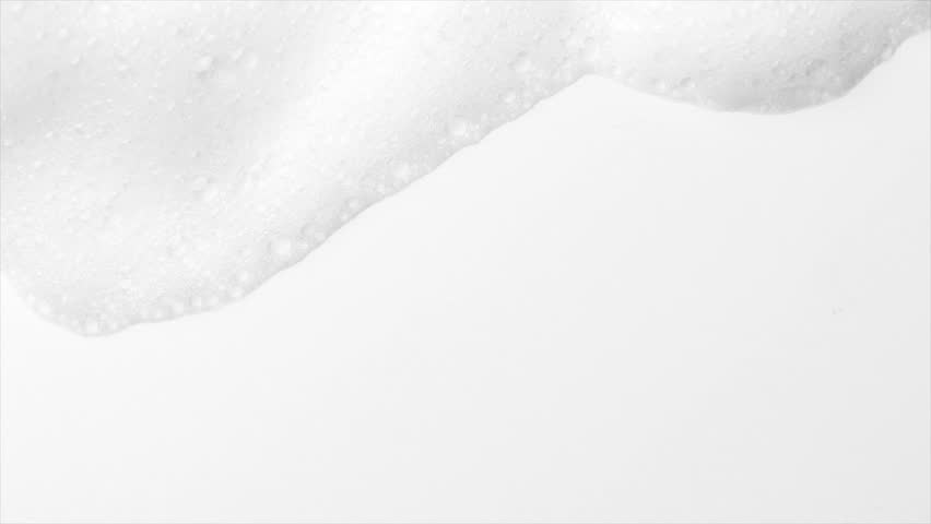 Foam bubbles background. Moving Soap foam popping bubble, white backdrop. Soap sud macro structure. Soap foam close-up. Clean, cleaning concept, laundry, shower 